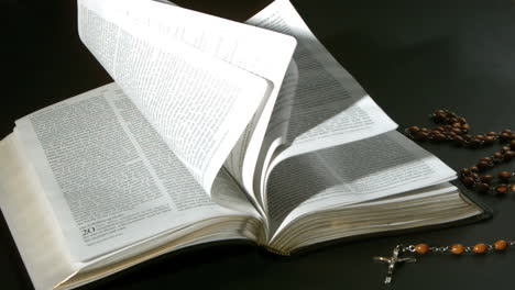 Páginas-De-La-Biblia-Girando-En-El-Viento-Junto-A-Rosarios