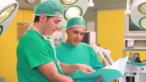 Two-surgeons-smiling-while-holding-files-in-a-surgery-theater