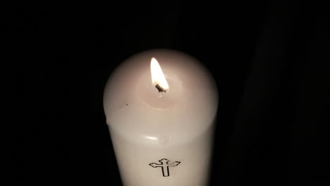 Candle-with-cross-embellishment-burning-and-being-blown-out