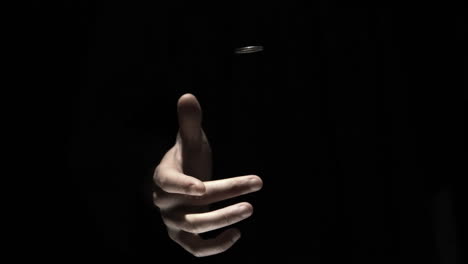 Hand-flipping-a-coin-on-black-background