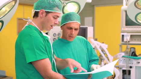 Two-surgeons-smiling-while-holding-files-in-a-surgery-theater