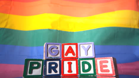 Bandera-Del-Arco-Iris-Moviéndose-En-La-Brisa-Con-Bloques-Del-Orgullo-Gay-En-Frente