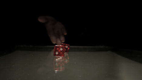 Hand-throwing-two-red-dice-onto-table