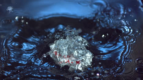 Miniature-model-house-falling-into-blue-water-and-floating