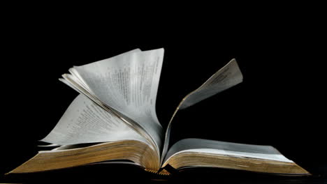 Pages-of-the-bible-turning-in-the-wind-on-black-background