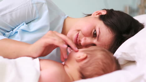 Mother-looking-at-her-sleeping-baby-head-to-head-in-a-bed