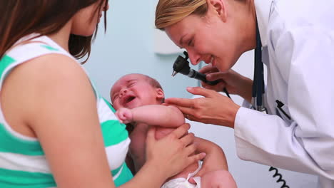 Arzt-Untersucht-Ein-Baby-Mit-Einem-Otoskop-In-Den-Armen-Seiner-Mutter