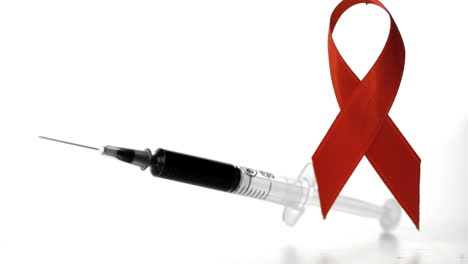 Syringe-falling-over-in-front-of-a-red-ribbon-