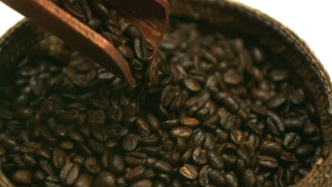 Coffee-beans-pouring-from-wooden-spoon-to-basket