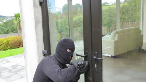 Burglar-opening-lock-on-door