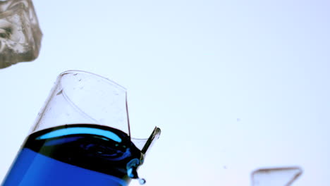 Ice-falling-and-breaking-glass-of-blue-liquid