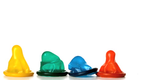Four-colourful-condoms-falling-on-white-background