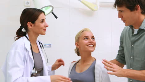 Smiling-female-doctor-talking-to-a-pregnant-woman-and-her-husband