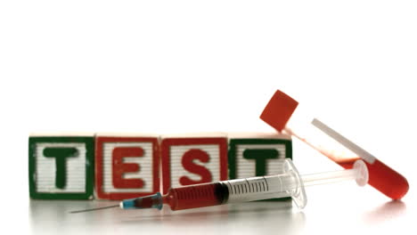 Syringe-falling-in-front-of-test-tube-and-blocks-spelling-test