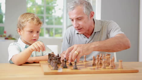 Child-learning-to-play-chess-with-his-grandpa