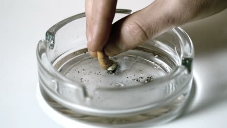 Hand-extinguishing-cigarette-in-empty-ashtray