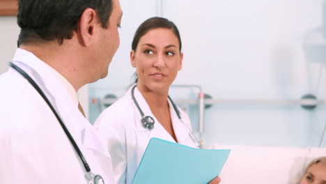 Female-and-male-doctors-standing-next-to-a-patient