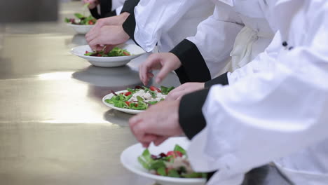 Vier-Köche-An-Der-Theke-Bereiten-Salat-Zu