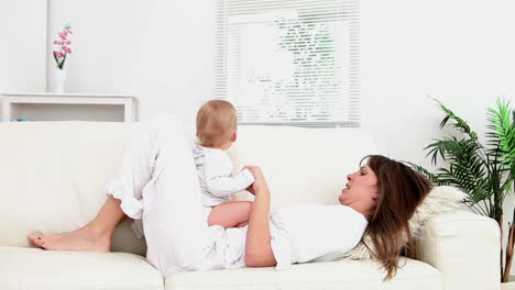 Woman-lying-on-the-sofa-while-holding-a-baby
