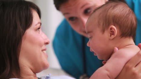 Madre-Feliz-Sosteniendo-A-Un-Bebé-En-Pañales-Con-Un-Médico