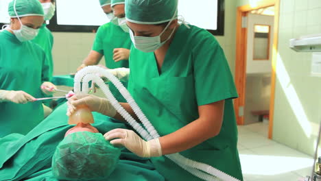 Female-surgeon-placing-an-oxygen-mask-on-the-face-of-an-unconscious-patient