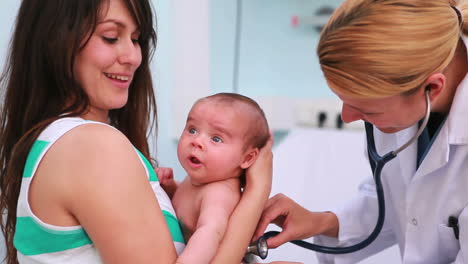 Mutter-Mit-Einem-Neugeborenen-Im-Arm-In-Einem-Untersuchungszimmer-Mit-Einem-Arzt-Mit-Einem-Stethoskop