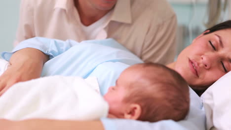 Father-looking-at-his-wife-and-a-newborn-baby-sleeping