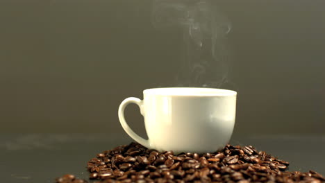 Dampf-Steigt-Aus-Kaffeetasse-Auf-Einem-Haufen-Kaffeebohnen-Auf