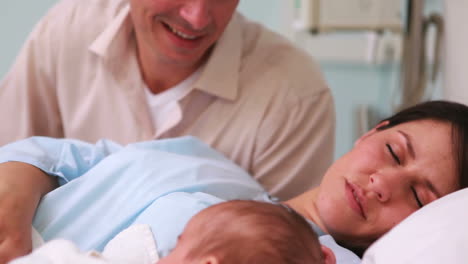 Father-looking-at-his-sleeping-wife-and-a-newborn-baby