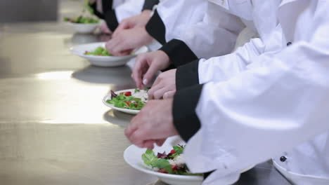 Four-cooks-preparing-salad-on-the-counter