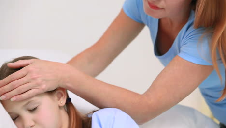 Woman-placing-her-hands-on-the-forehead-of-a-girl-in-a-bed