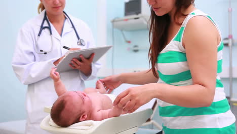 Frau-Und-Arzt-Mit-Einem-Baby-Auf-Einem-Tisch