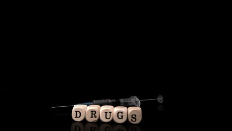 Syringe-falling-and-rolling-towards-dice-spelling-drugs