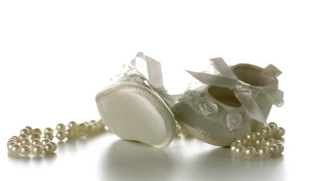 Babyschuhe-Fallen-Auf-Eine-Perlenkette