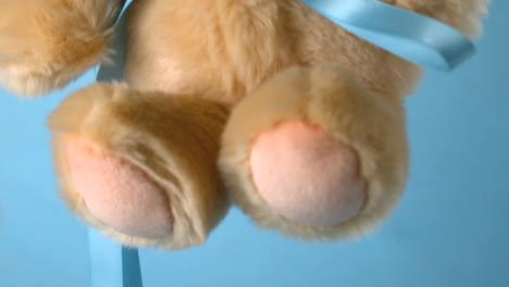 Teddy-bear-falling-on-blue-background-close-up