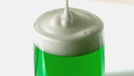 Close-up-of-foam-pouring-onto-pint-of-green-beer