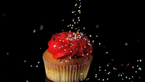Sprinkles-falling-onto-red-iced-cupcake