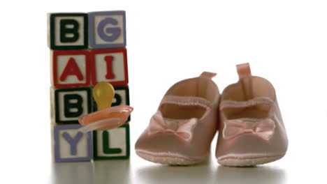 Yellow-soother-falling-besides-baby-blocks-and-booties