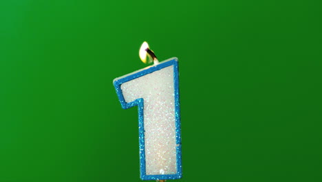 One-birthday-candle-flickering-and-extinguishing-on-green-background