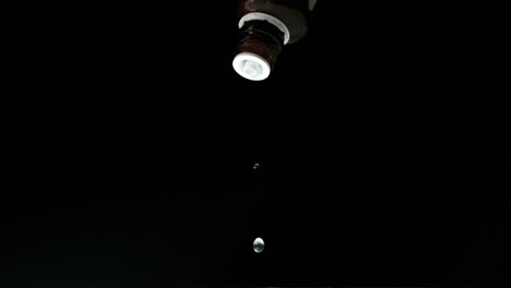 Medicine-dripping-from-bottle-on-black-background