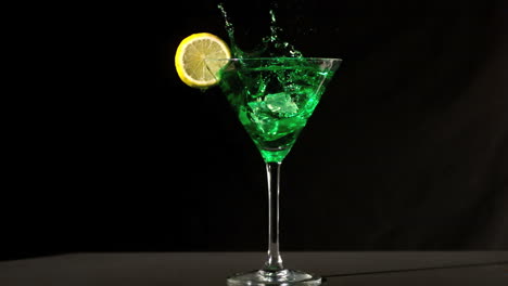 Ice-cube-falling-into-green-cocktail