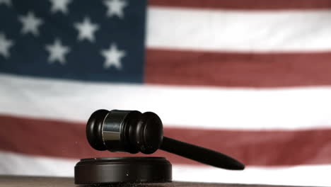 Gavel-dropping-onto-sounding-block-with-american-flag-in-background