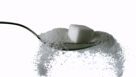 Sugar-cube-falling-onto-spoon-full-of-sugar