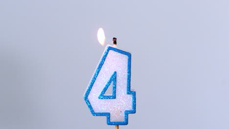 Four-birthday-candle-flickering-and-extinguishing-on-blue-background