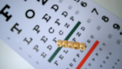 Dice-spelling-out-sight-falling-onto-eye-test-beside-glasses