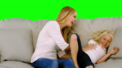 Mother-and-daughter-tickling-each-other-on-sofa-in-slow-motion
