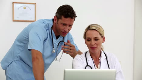 Two-doctors-using-a-laptop-together-in-their-office