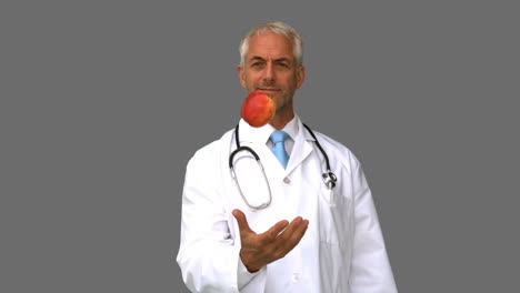 Doctor-throwing-an-apple-on-grey-screen