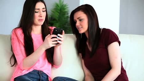 Brunette-woman-showing-her-smartphone-to-her-friend