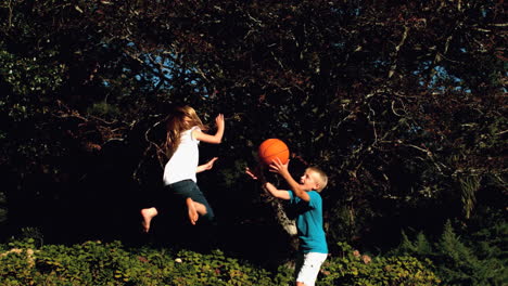 Geschwister-Haben-Spaß-Mit-Einem-Basketball-Auf-Einem-Trampolin